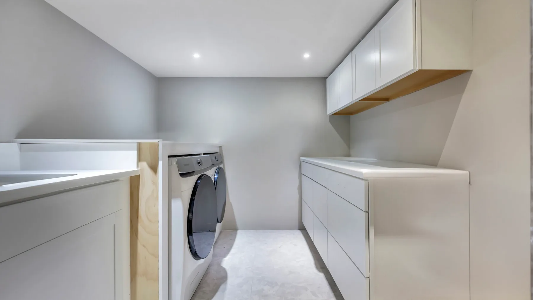 A laundry room with front-loading laundry machines and white cabinetry.