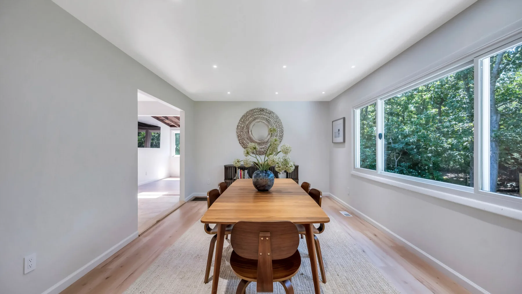 A dining area with a wooden table and large windows.