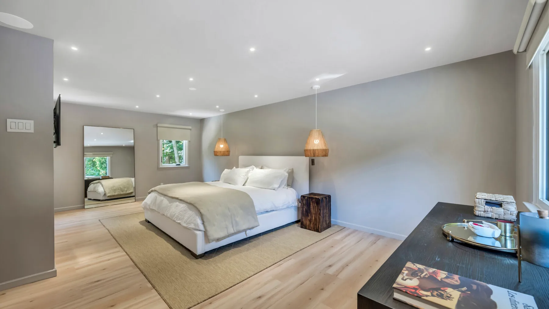 A bedroom with a bed, bedside table, and wood flooring.