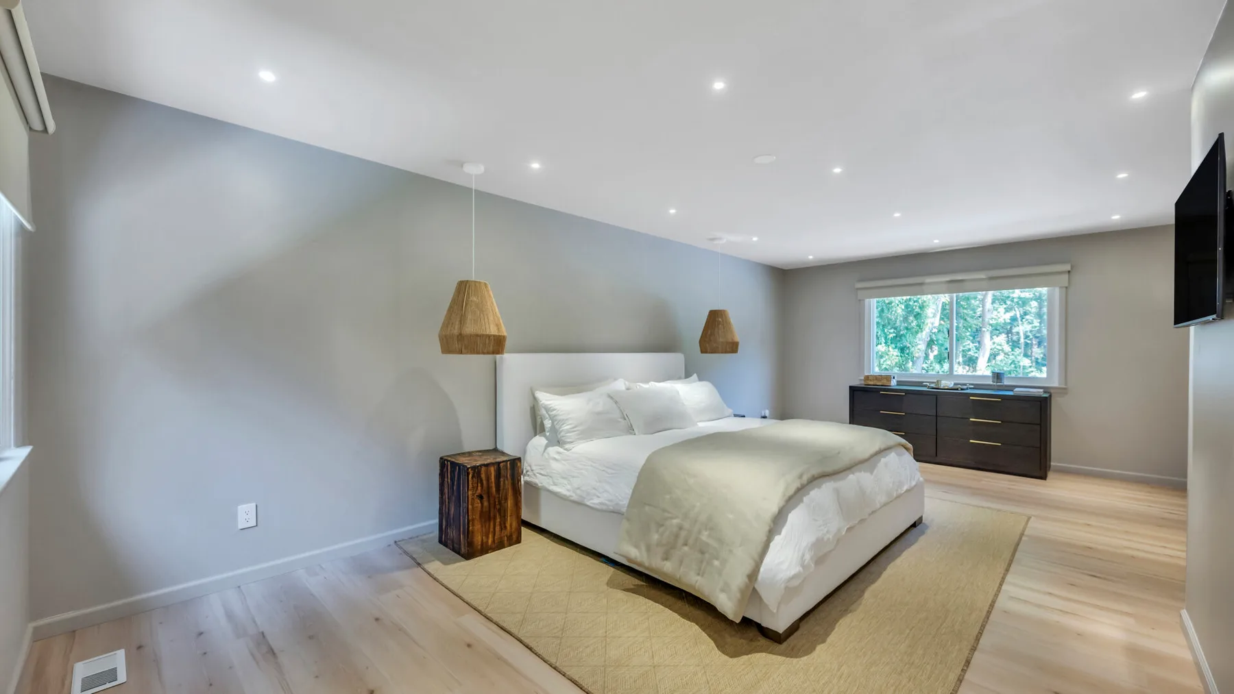 A bedroom with a bed, bedside tables, and a dresser beneath the window.