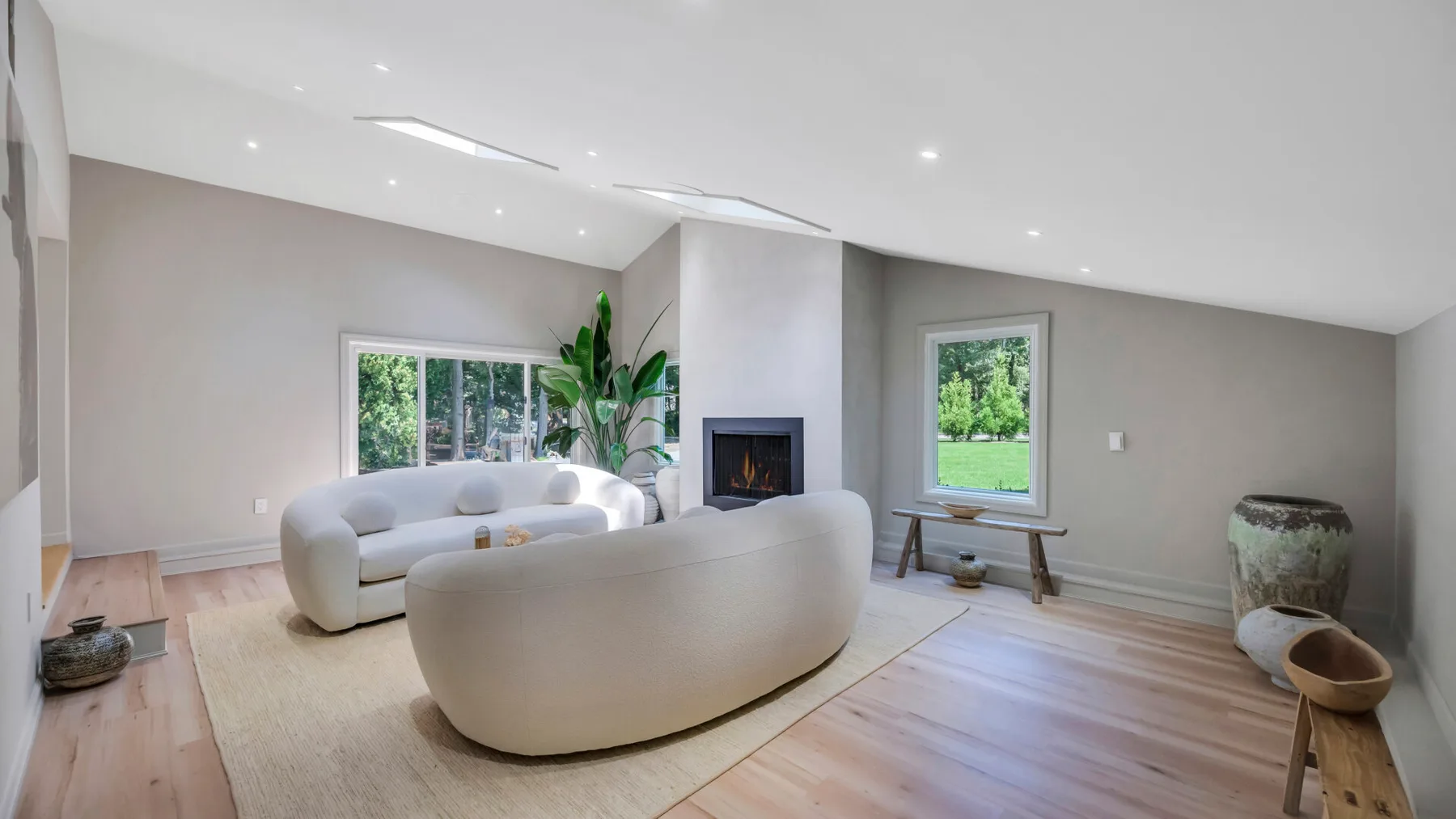A bright living room with curved seating, a fireplace, and large windows.