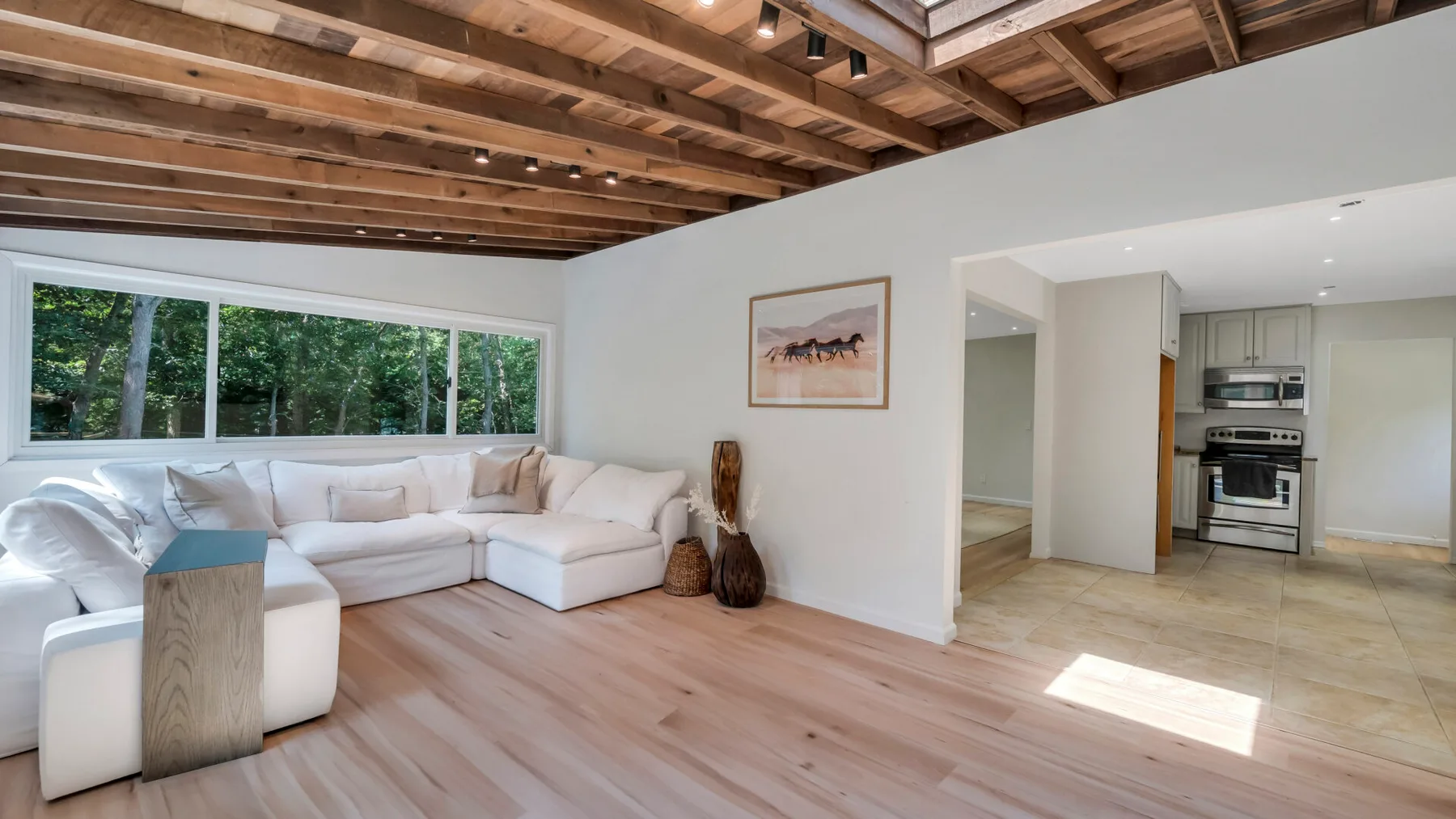 A bright living room with an L-shaped seating area and an open kitchen.