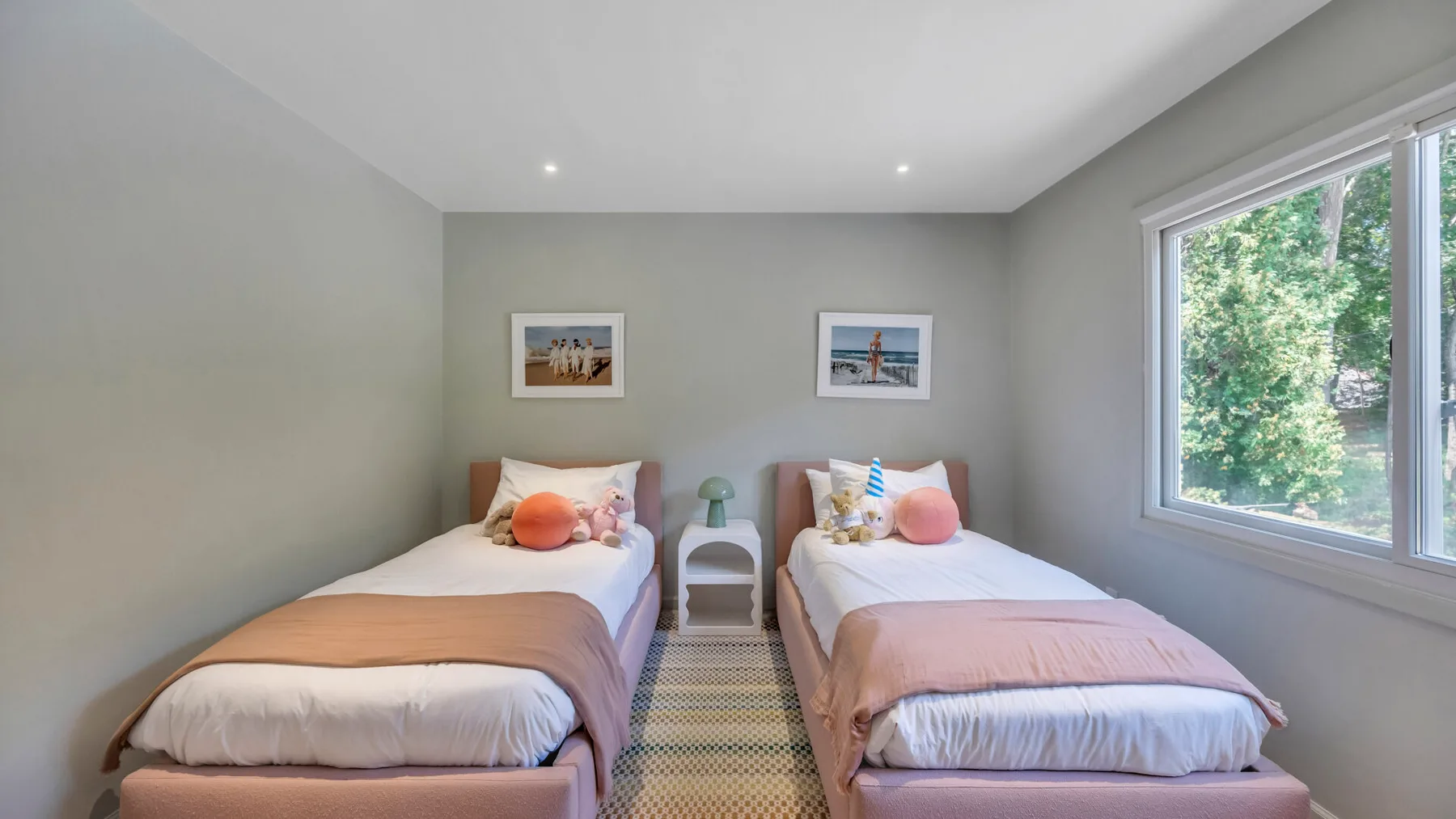 A bedroom with two single beds and a large window overlooking greenery.