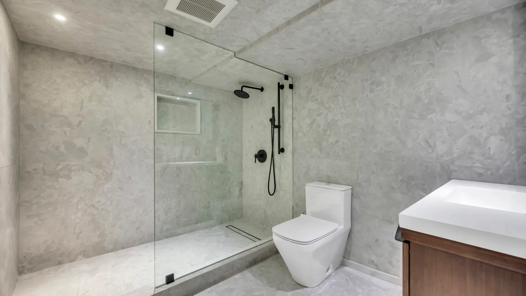 A bathroom with a glass shower, toilet, and vanity.