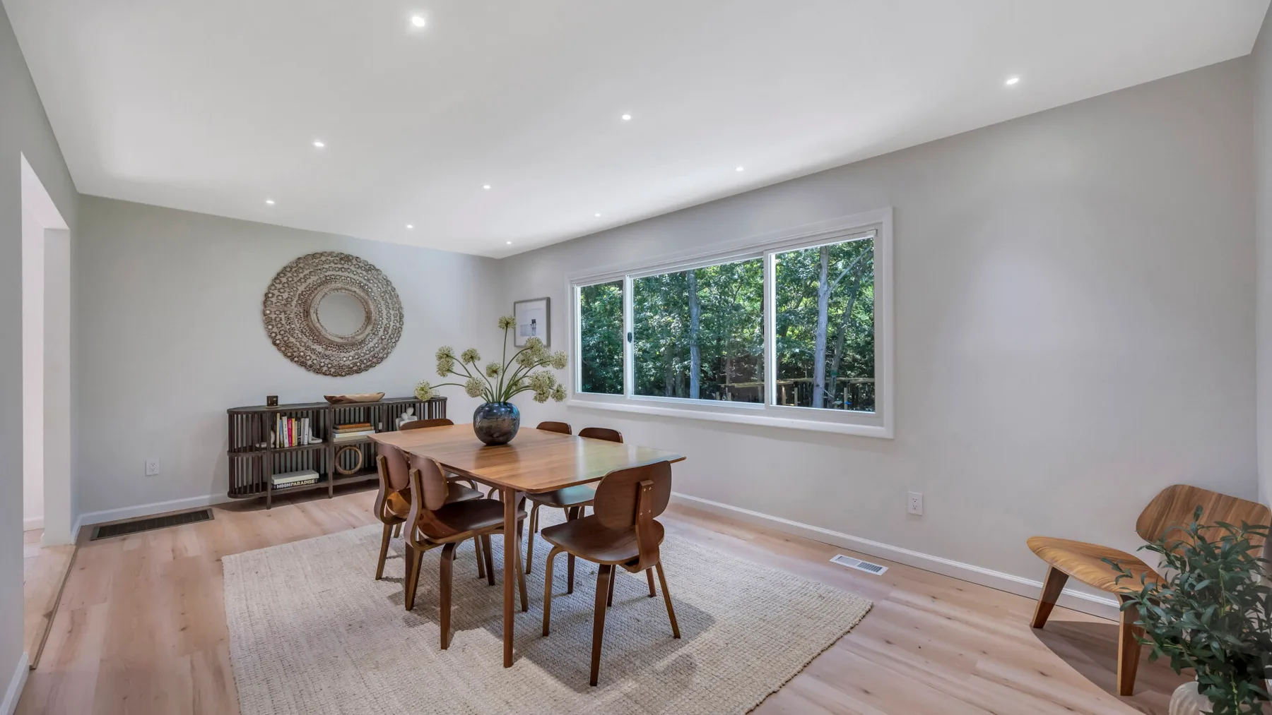 A bright dining room with a wooden table beside a large window.