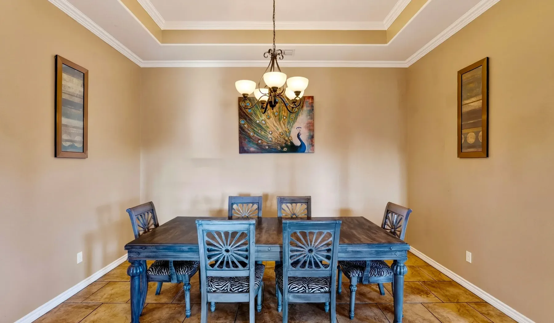 Comedor con mesa de madera, asientos azules y una lámpara de araña.
