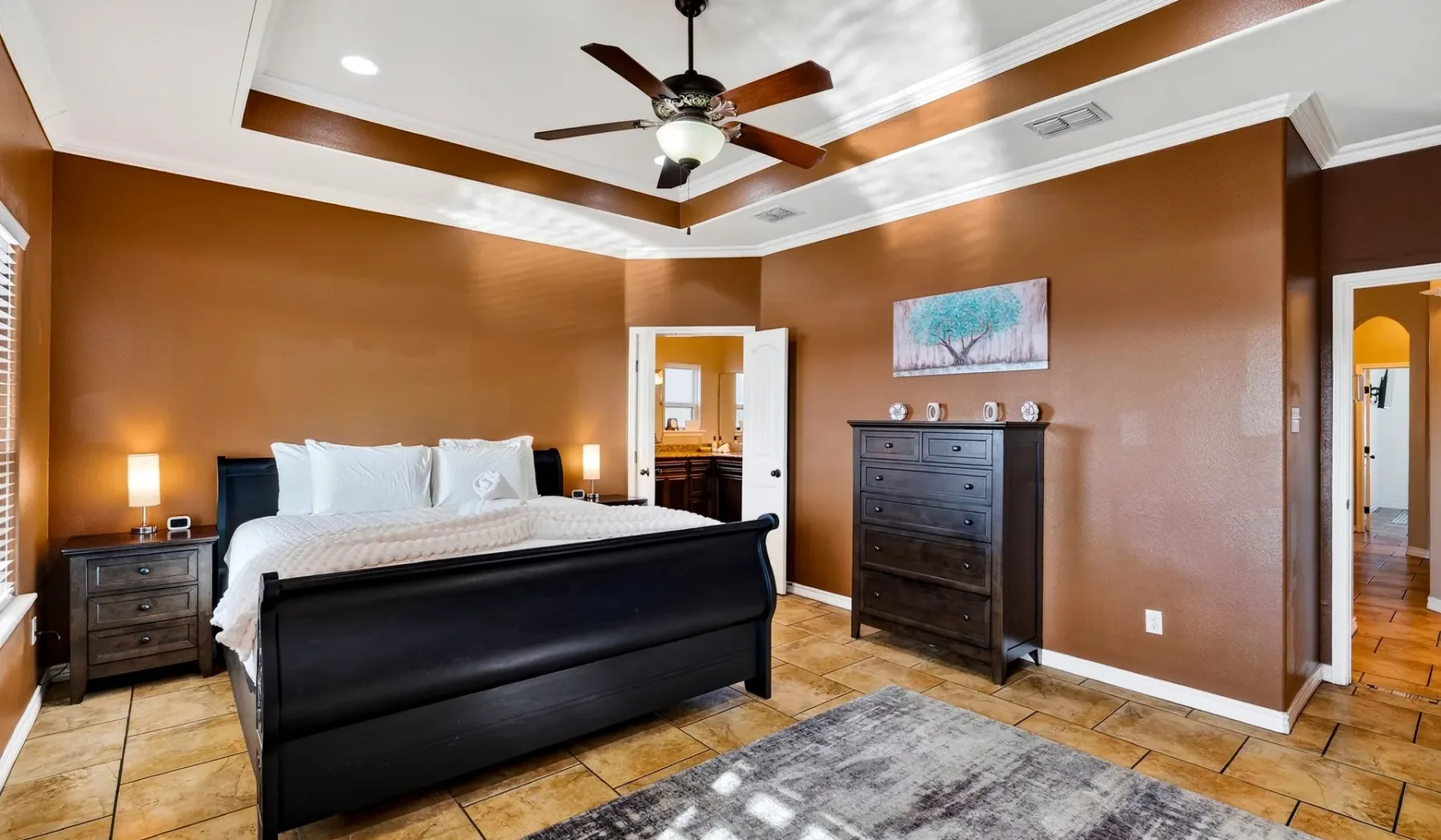 Un dormitorio con una cama grande, muebles de madera oscura y un ventilador de techo.