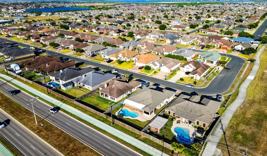 Vista aérea de un barrio residencial con una carretera en primer plano.