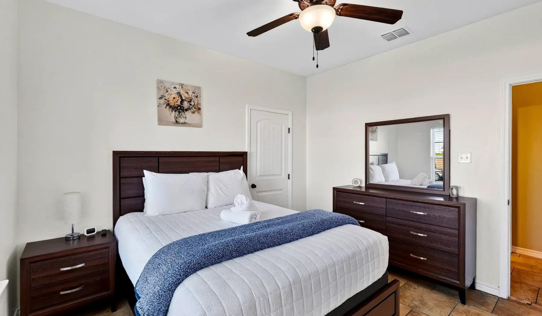 Dormitorio con una cama bien tendida y muebles de madera oscura.