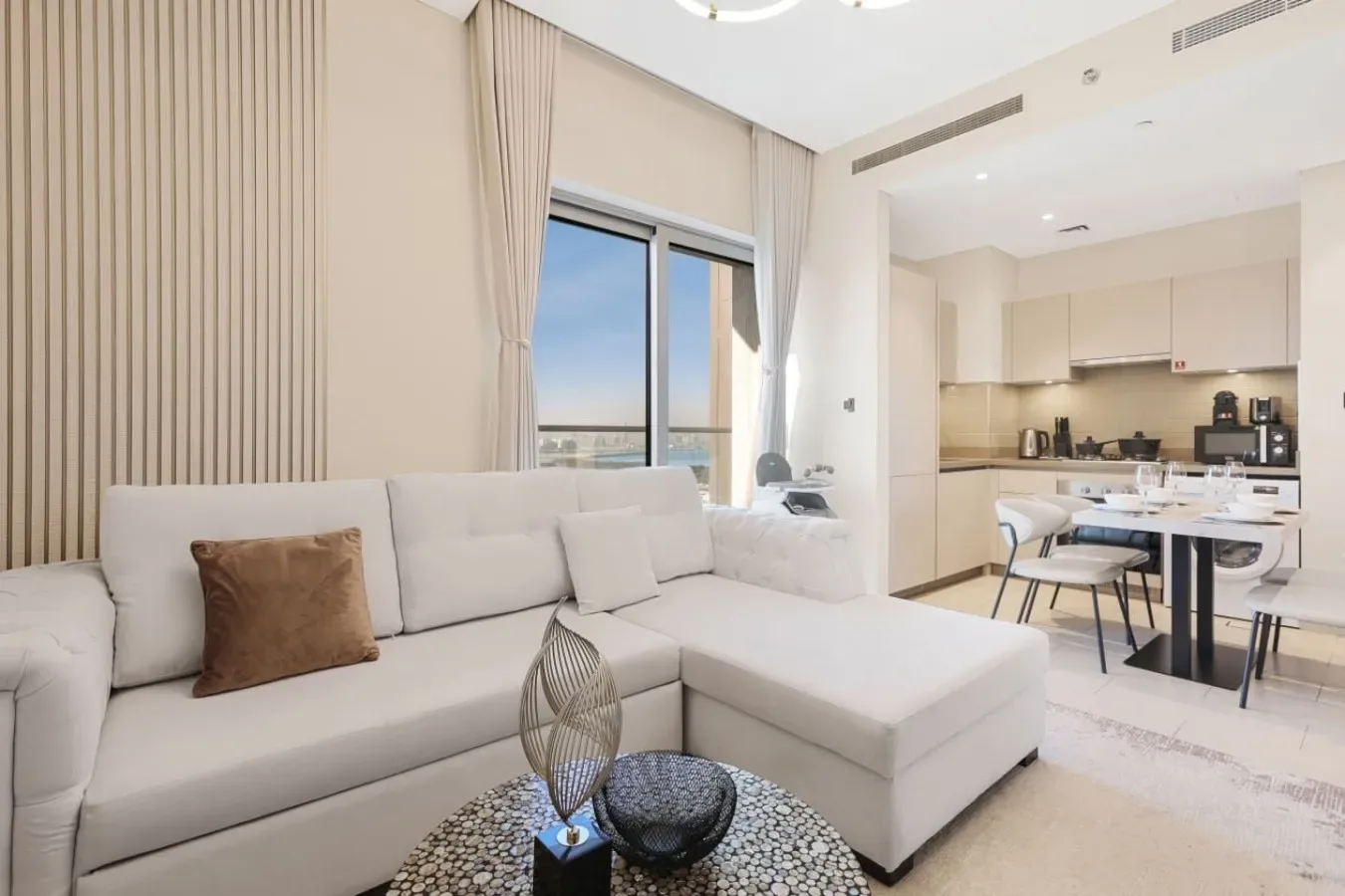 Una luminosa sala de estar y cocina de concepto abierto con sofá seccional y mesa de comedor.