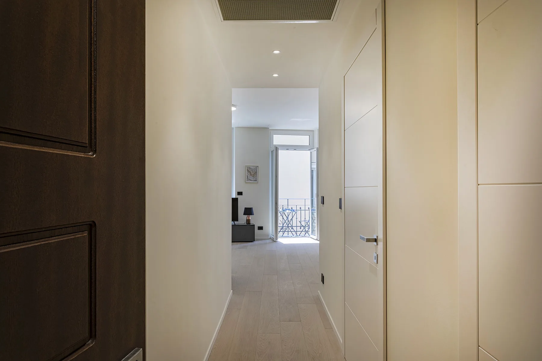 A bright hallway leads to a living area with a window at the far end.
