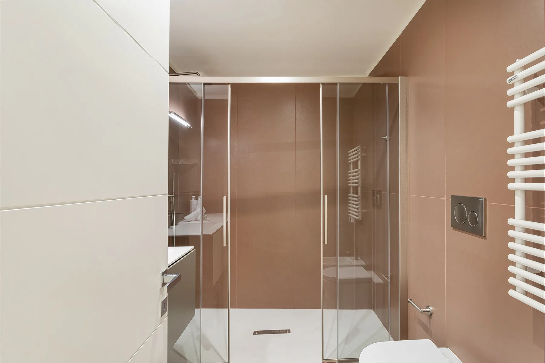 A modern bathroom with a glass shower and wall-mounted towel radiator.