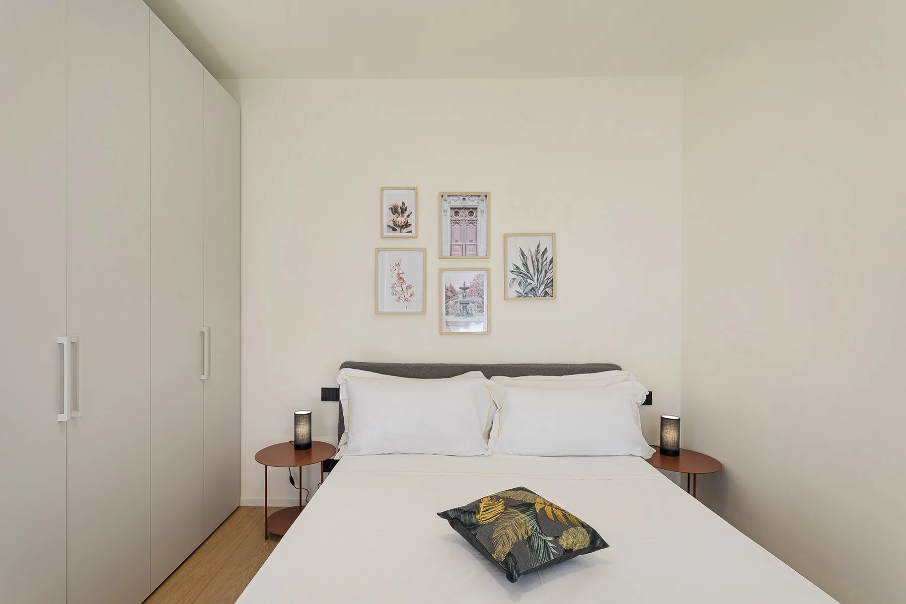 A bedroom with a neatly made bed and framed artwork above the headboard.