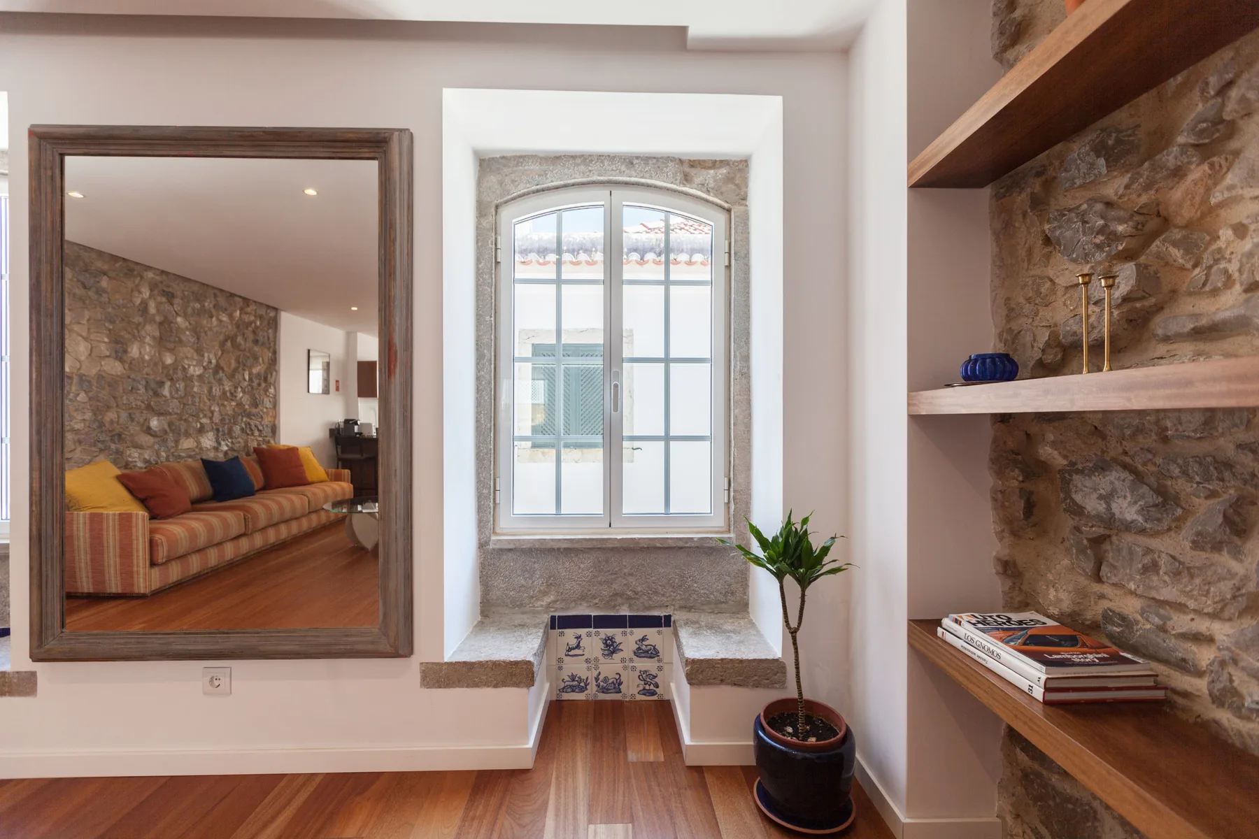 Una sala de estar con una ventana grande, una planta en maceta y estantes empotrados.