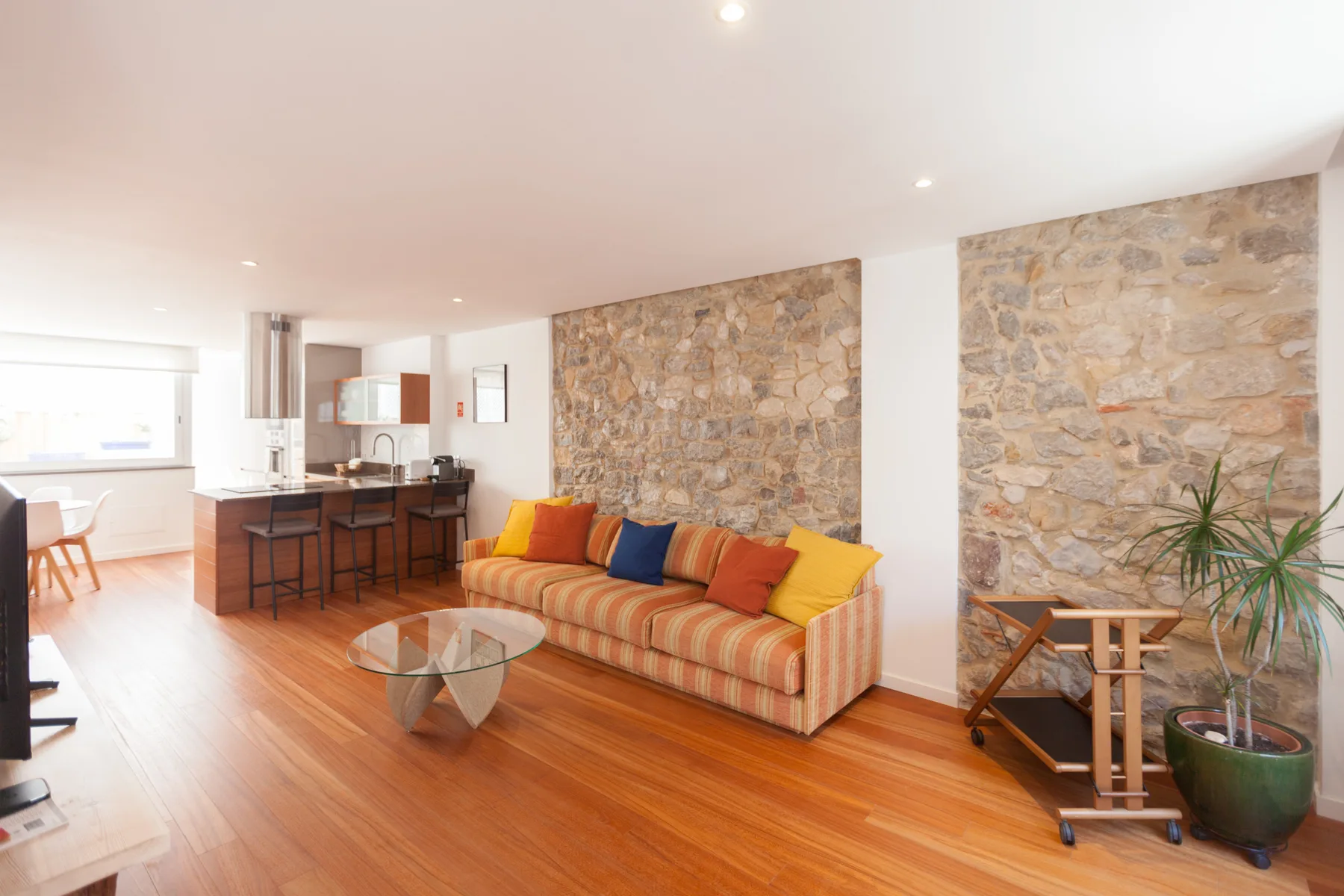Sala de estar con asientos a rayas, una mesa de centro y cocina abierta.