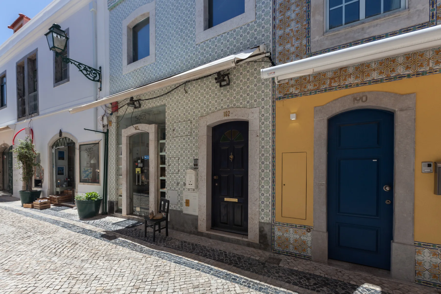 Una calle empedrada bordeada de fachadas coloridas y entradas.