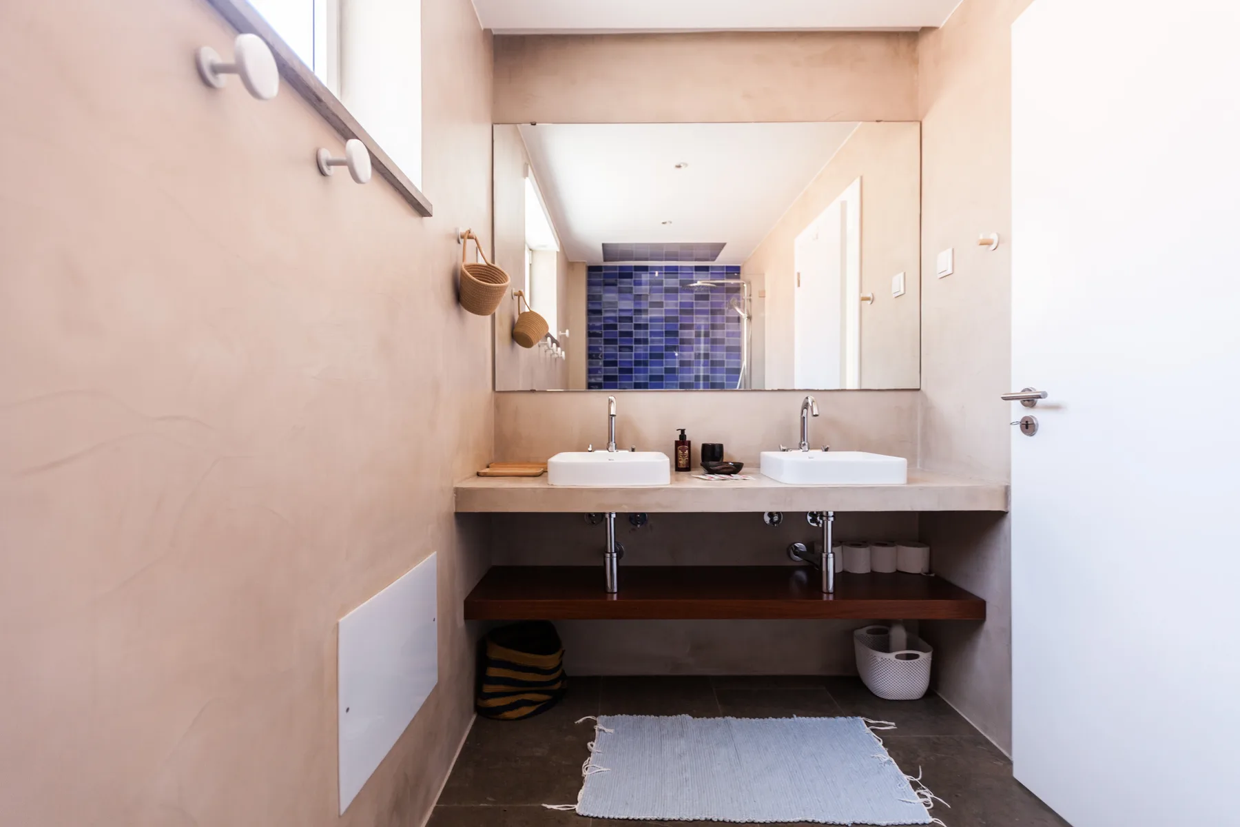 Un lavabo de baño con dos lavabos está bajo un espejo grande.