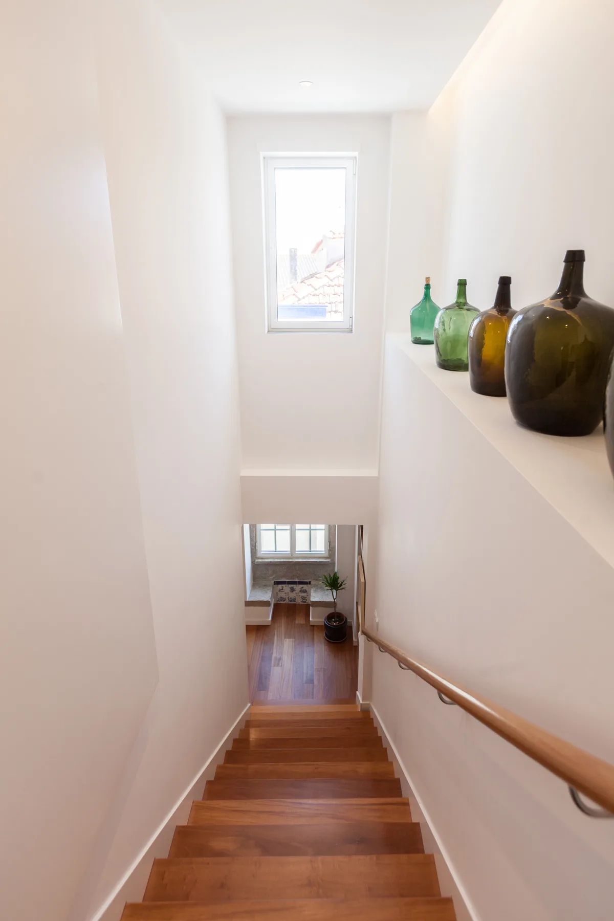 Una escalera interior estrecha desciende hacia una pequeña habitación con suelo de madera.