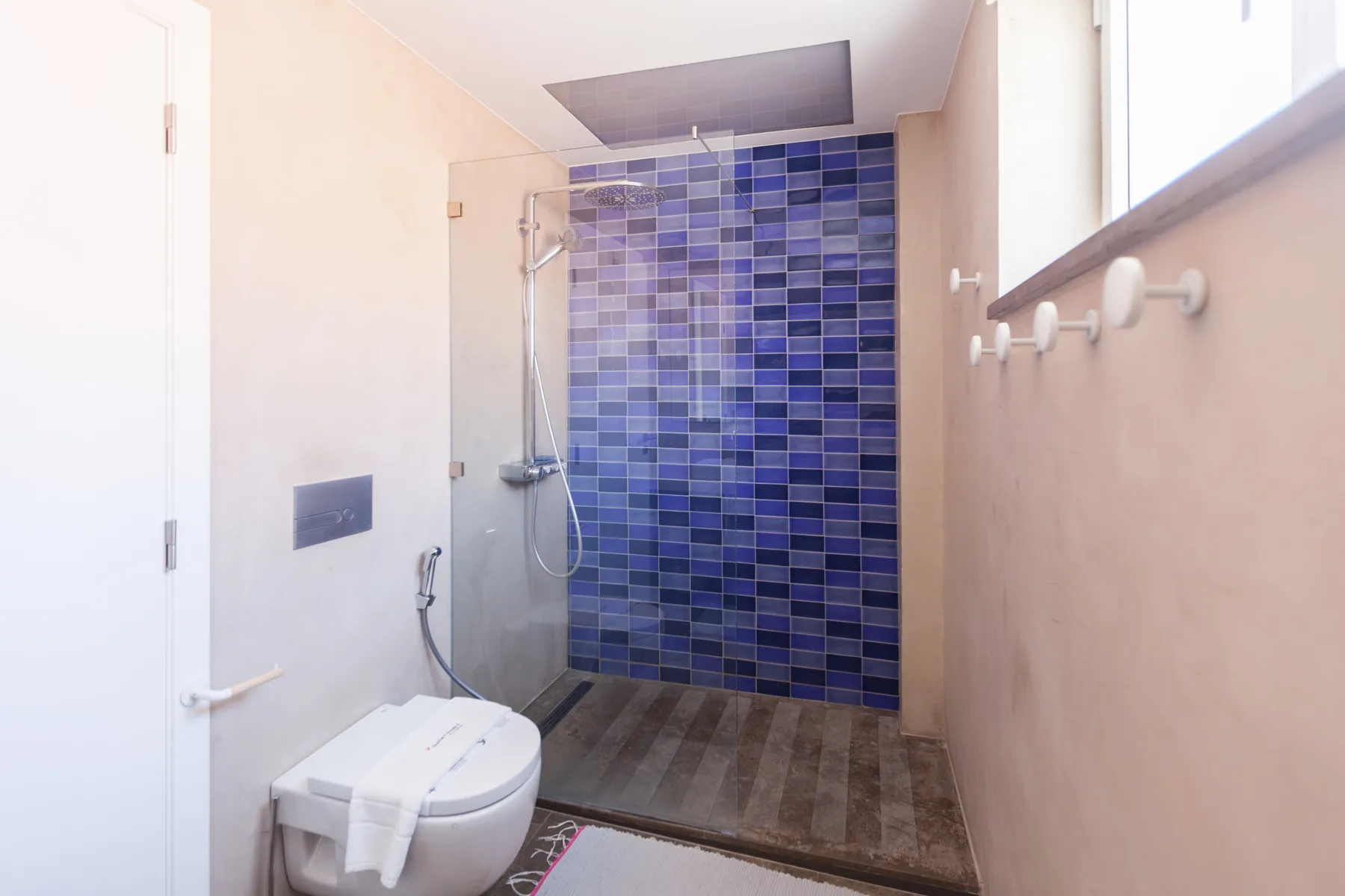 Un baño con una zona de ducha revestida de azulejos azules.