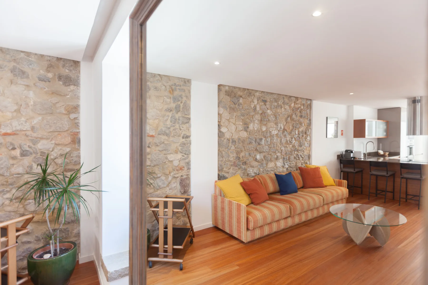 Una sala luminosa con asientos a rayas y una mesa de centro de vidrio.