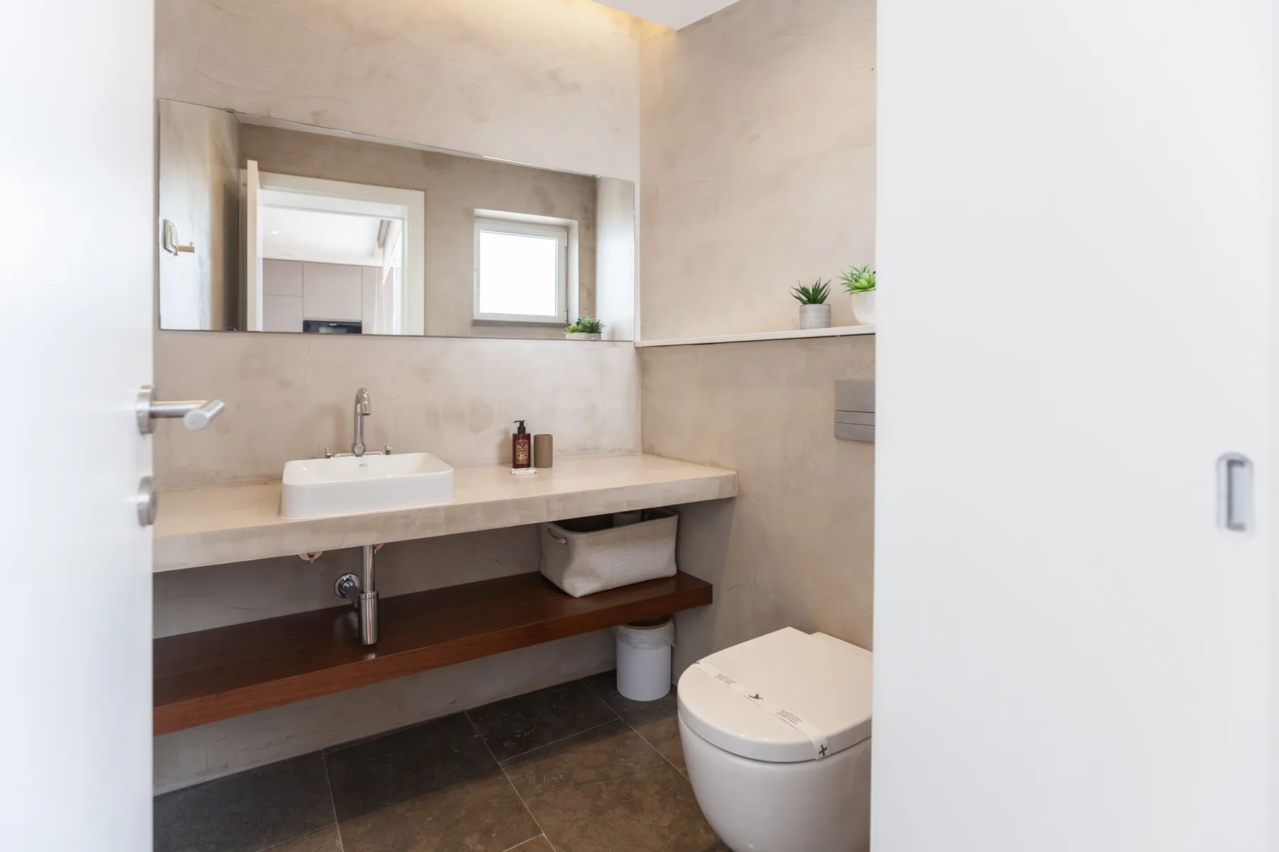 Un baño con lavabo, inodoro y un espejo amplio.