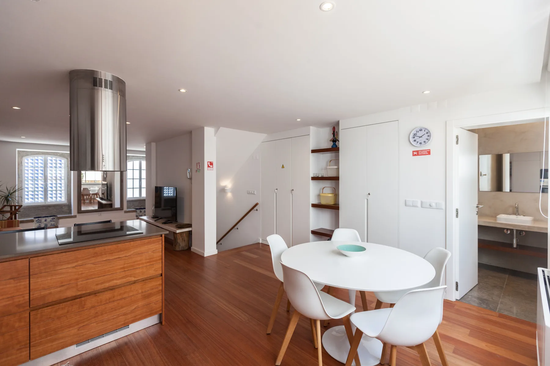 Una cocina y comedor diáfanos y luminosos, con una mesa redonda y asientos blancos.