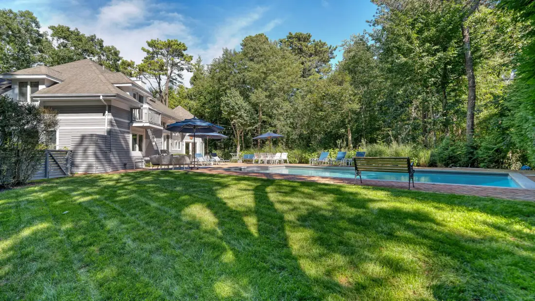 Una casa y una piscina al aire libre están junto a un amplio césped.