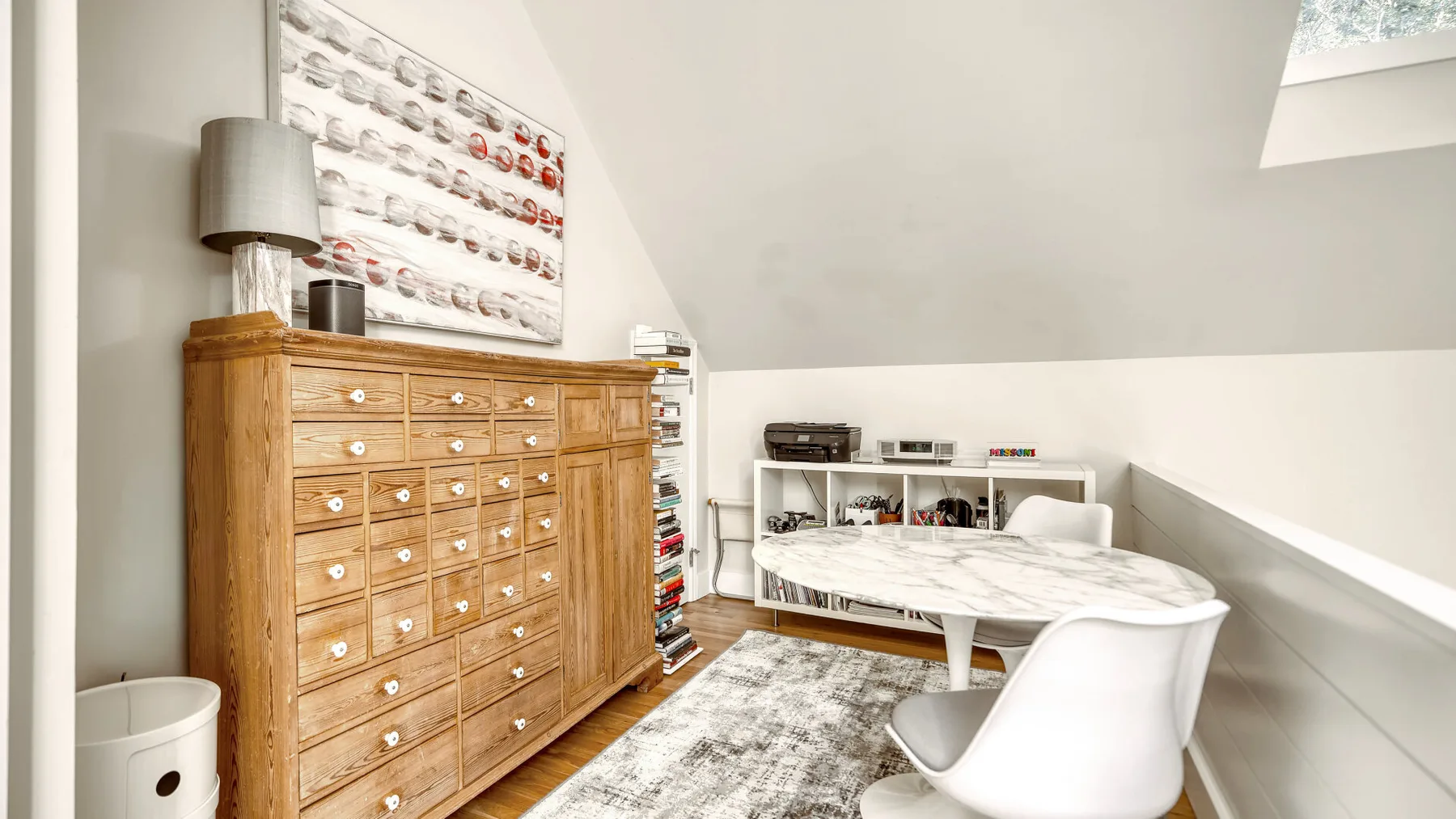 Un ático luminoso con un mueble de madera y una mesa rodeada de asientos.