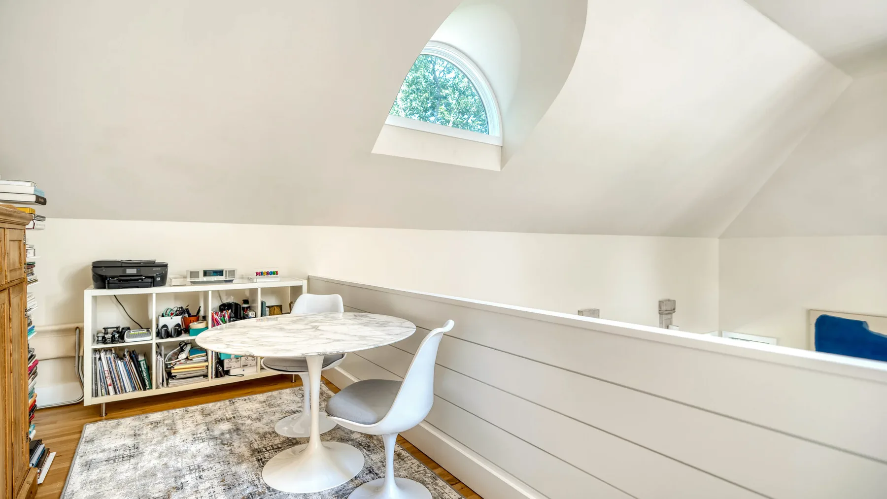 Un comedor luminoso en un espacio abuhardillado, con mesa, asientos y tragaluz.