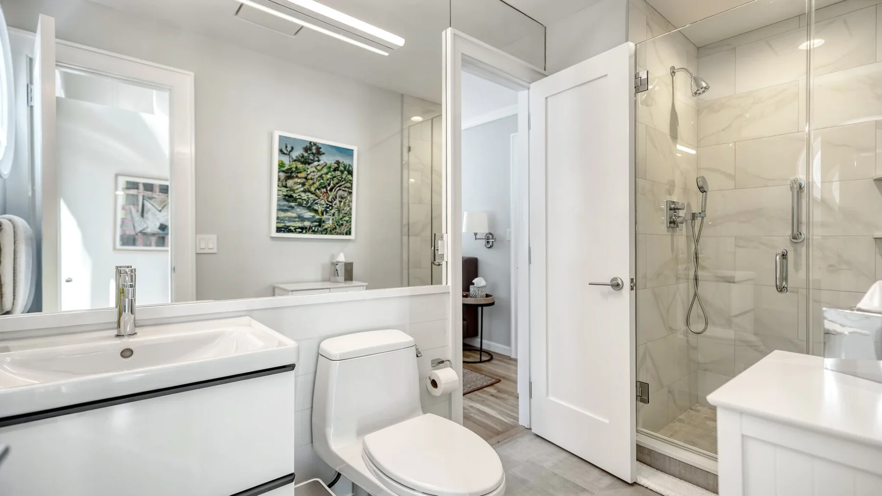 Un baño luminoso con ducha de vidrio y lavabo blanco.