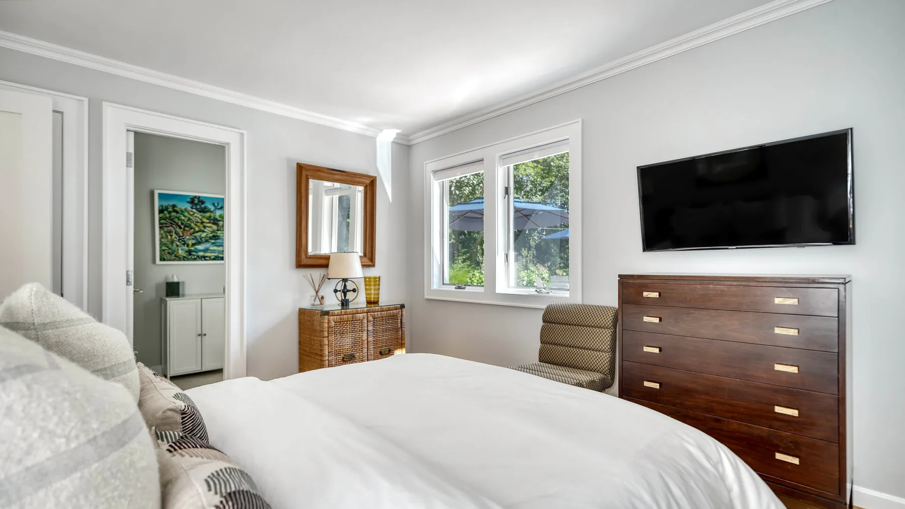Un dormitorio con una cama, una cómoda y un televisor en la pared.