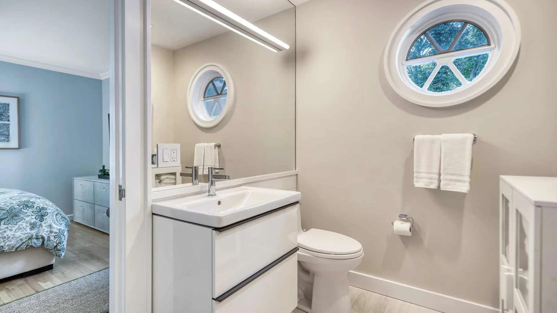 Un baño con lavabo, inodoro y ventanas redondas.