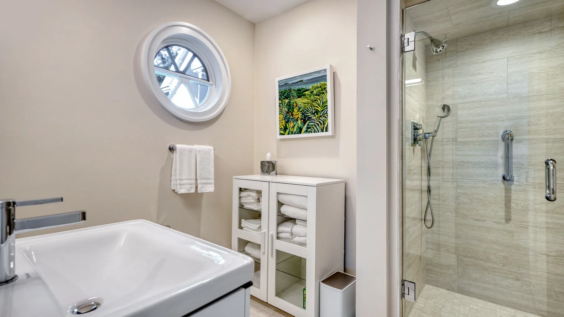 Un baño con bañera, mueble de lavabo y ducha con mampara de vidrio.