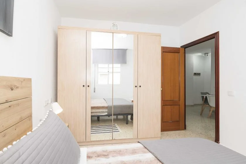 A bright bedroom with a mirrored wardrobe and a bed.