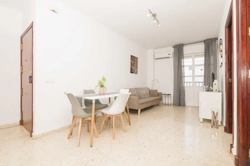 A bright living and dining area with a table, seating, and a window.