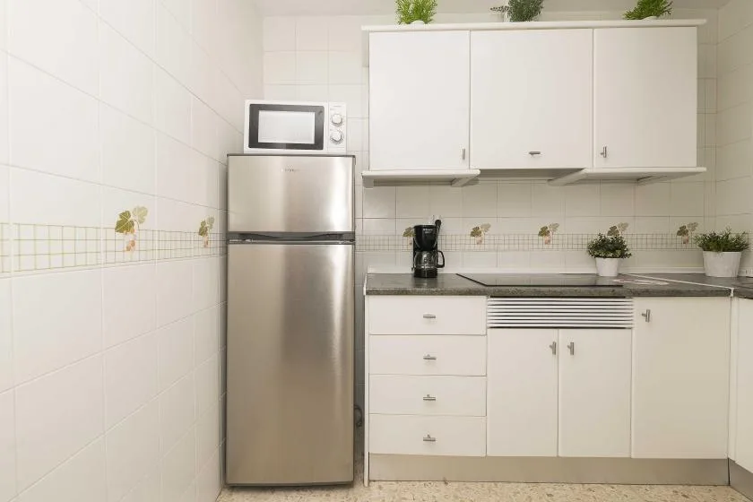 A bright kitchen with white cabinets, a stainless-steel refrigerator, and a countertop.