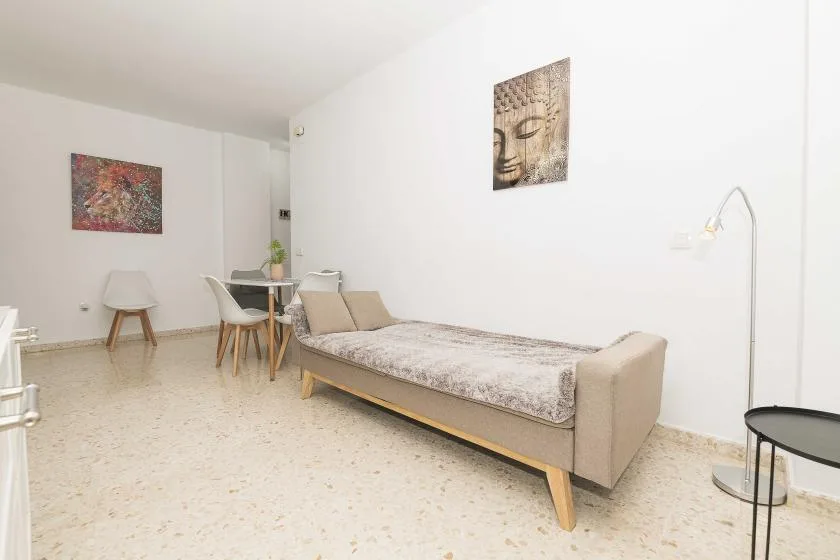 A bright living area with a daybed, dining table, and wall art.