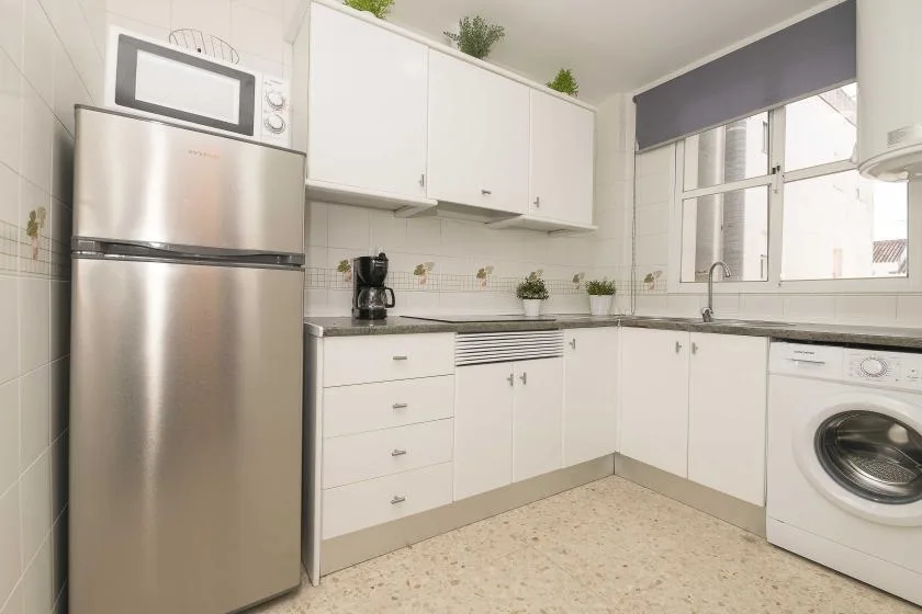 A bright kitchen with white cabinets, a countertop, and a washing machine.