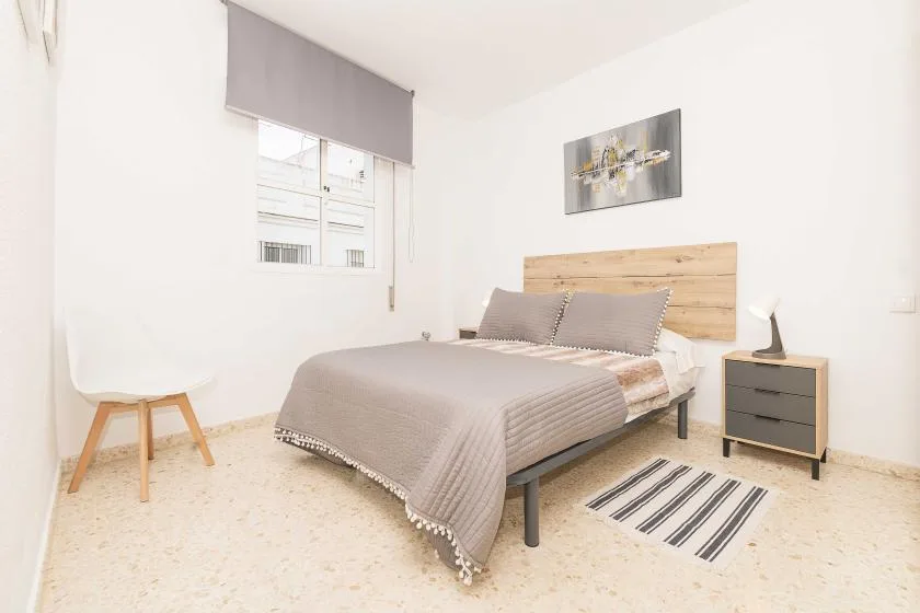 Bedroom with a bed, wooden headboard, and a window with a gray shade.