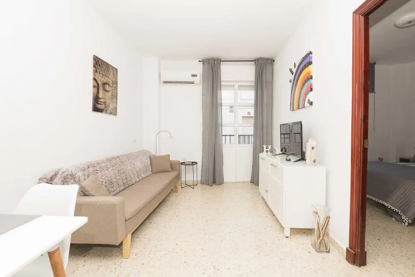 A bright living room with a beige sofa and white storage cabinet.