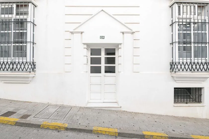 A white building facade with a central entrance and barred windows.