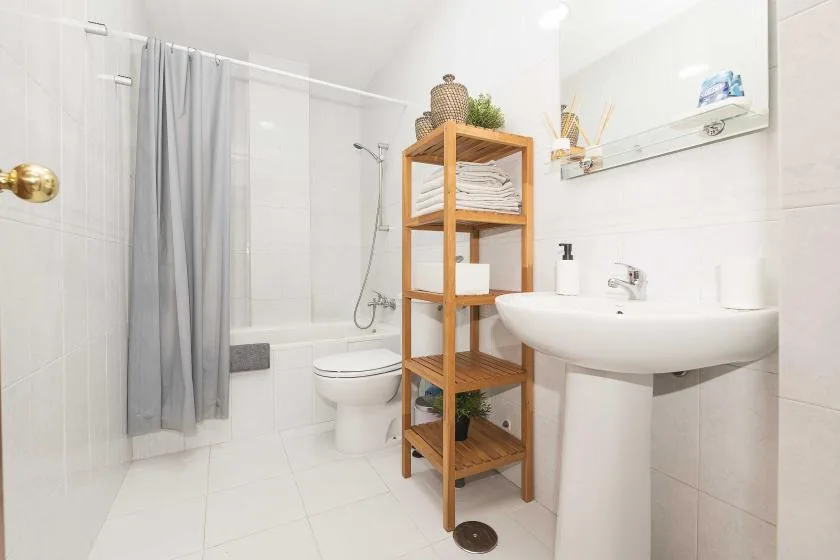 A bright bathroom with a sink, toilet, and shower curtain.