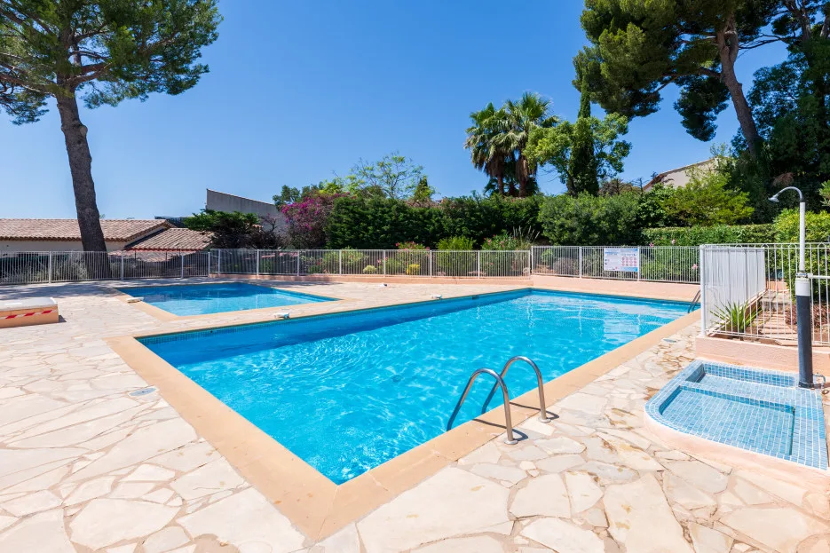 Piscina al aire libre con una piscina pequeña y poco profunda al lado y pavimento alrededor.