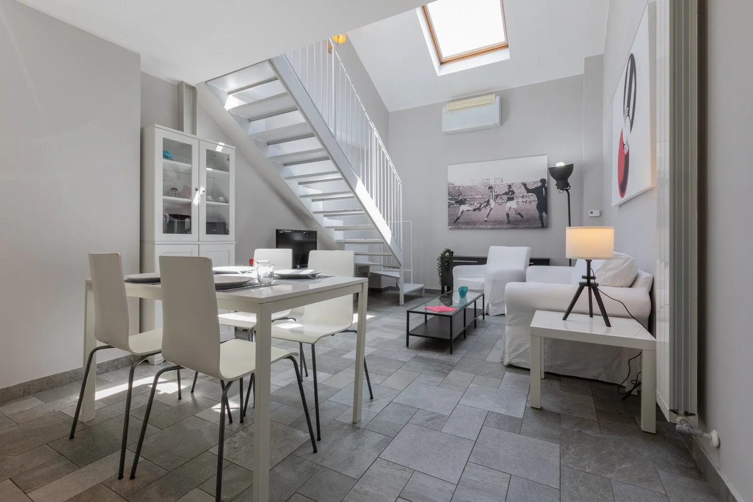Una luminosa sala de estar y comedor con mesa, asientos y una escalera.