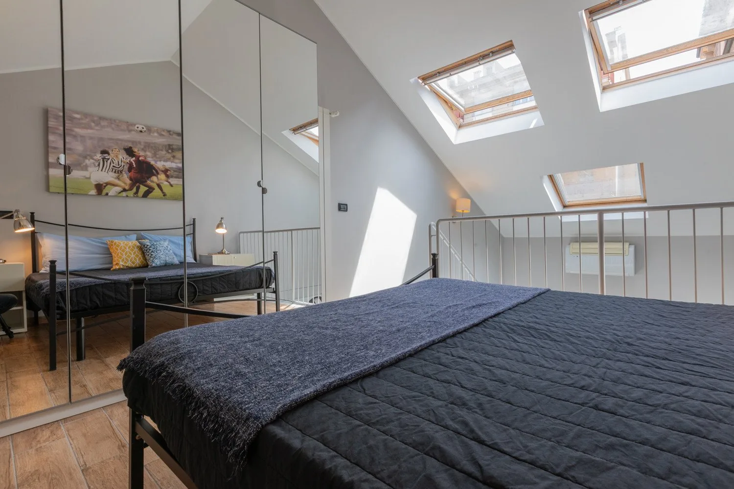 Un dormitorio con una cama grande bajo un techo inclinado y ventanas de tragaluz.
