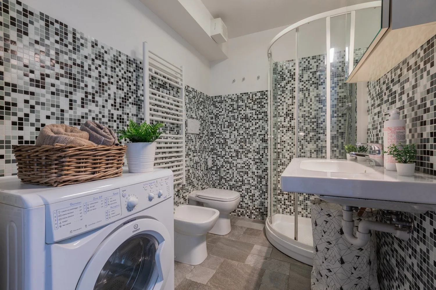 Un baño alicatado con ducha, lavabo, inodoro y lavadora.