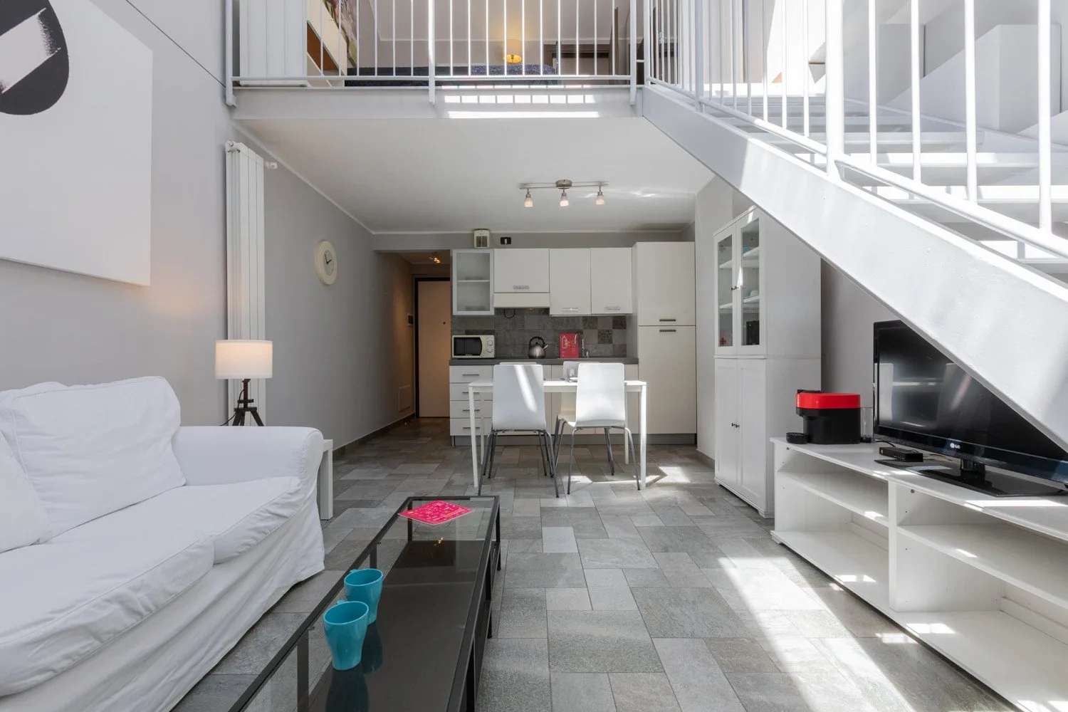 Una luminosa sala de estar de planta abierta con cocina y escalera.