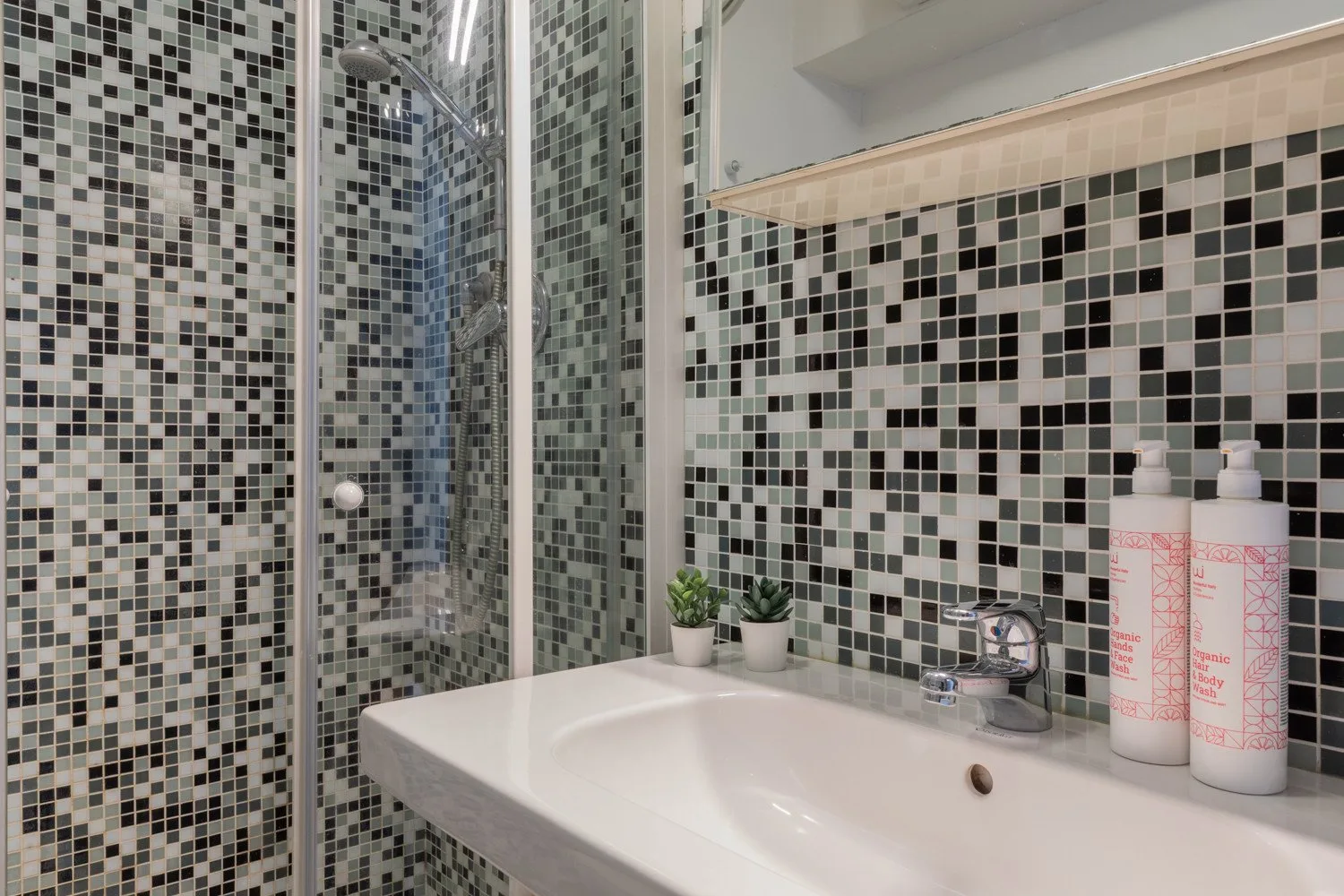 Un baño con azulejos, lavabo y ducha.