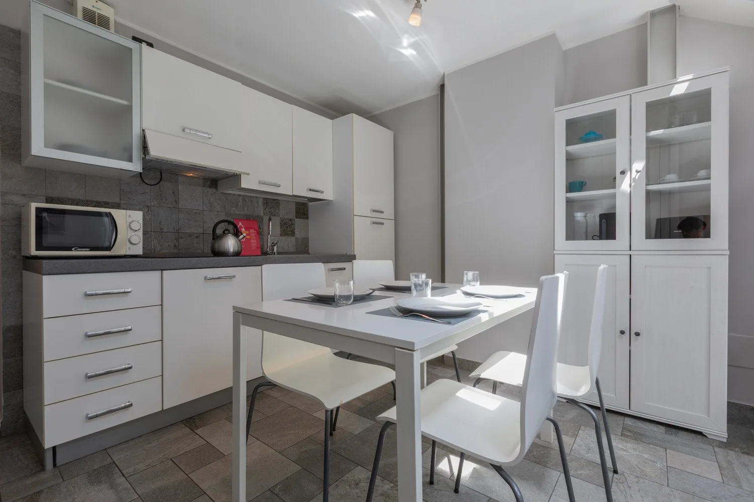 A modern kitchen and dining area with a table and white cabinetry.