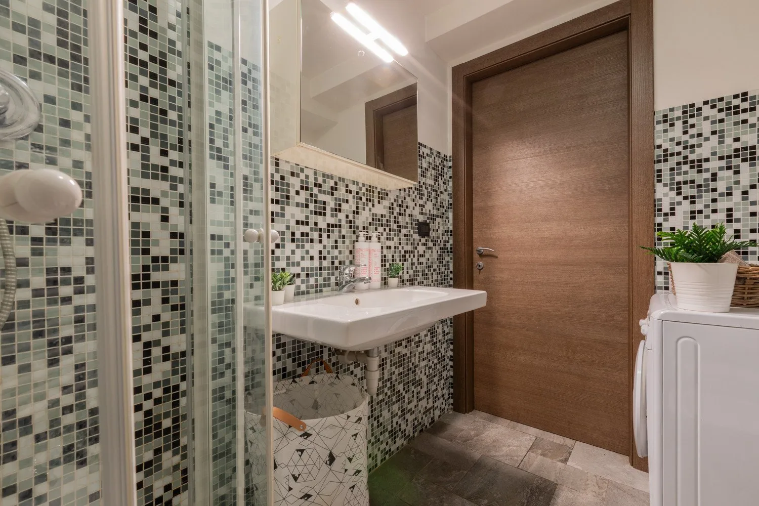 Un baño alicatado con un lavabo de pared y una puerta de madera.